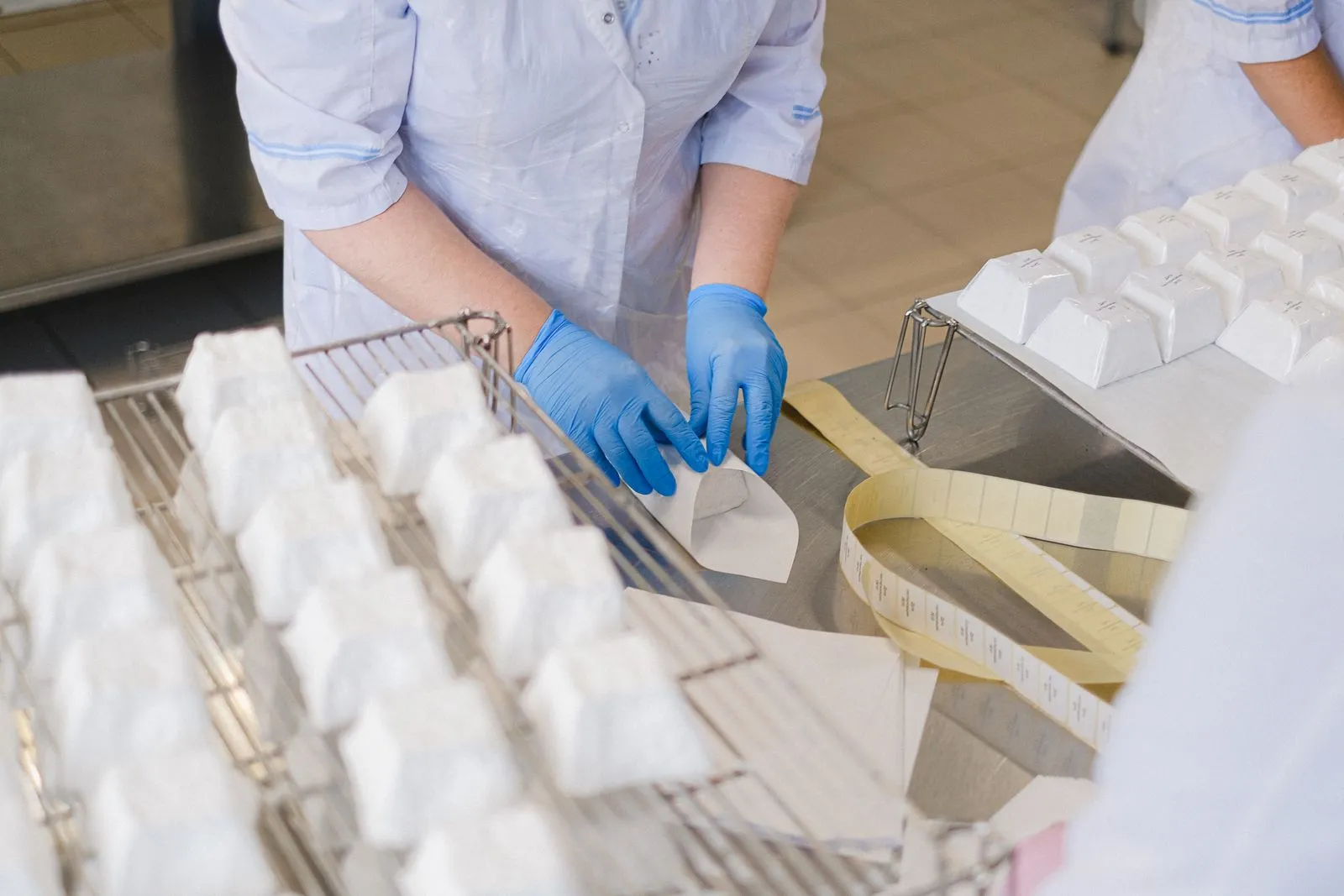 Käse wird in Papier eingeschlagen, daneben liegen Etikettenrollen